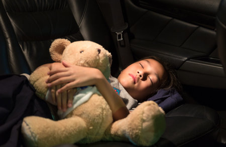 Asian girl sleeping in the back of a car,little girl fell asleep her teddy the arms