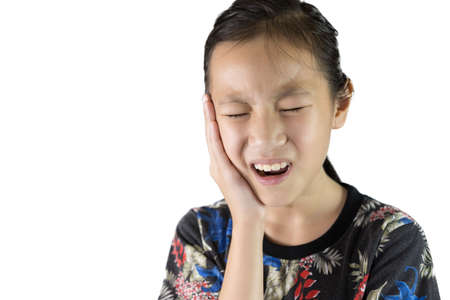 Asian girl suffering from toothache dental problem,child in pain emotion use hand touch cheek as suffer from toothache isolated on white backgroundの写真素材
