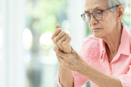 Asian senior woman is massaging her wrists,Elderly woman suffering from pain in hand,arthritis,beriberi or peripheral neuropathiesの写真素材