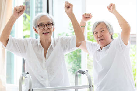 Happy two asian senior women raising fist and hurrah,time together,friends of elderly woman or sister smiling,laughing and raising hands,friendship of the old people,retirement ageの写真素材