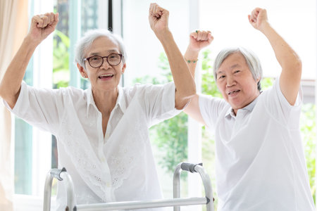 Happy two asian senior women raising fist and hurrah,time together,friends of elderly woman or sister smiling,laughing and raising hands,friendship of the old people,retirement ageの写真素材