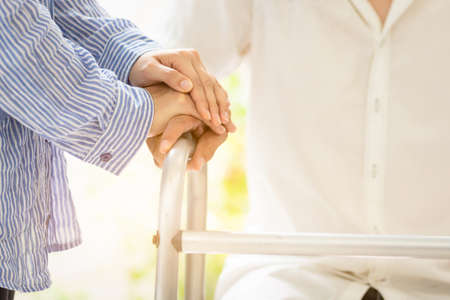 Asian family couple with walker during rehabilitation in home,young woman caregiver or wife hand holding hand of husband to support and help,family care conceptの写真素材