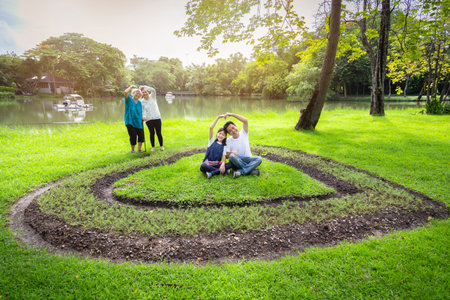 Happy asian family,daughter,father,mother,senior grandmother forming a heart with their hands,having fun,enjoy,laugh in outdoor park,cute child girl,elderly woman smile,love,generation,people conceptの写真素材