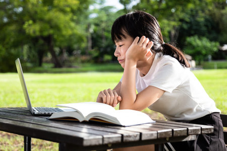Asian little child girl feeling boring while cramming,studying online,female student with laptop...