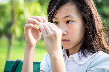 Asian beautiful child girl pulling her hair with her fingers in mental health problems,nervous system,brain system or schizophrenia,female psychiatric patient in trichotillomania hair-pulling disorderの写真素材