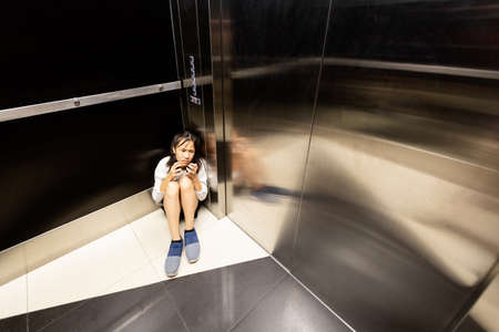Anxiety asian child girl having panic disease attack in an elevator,stressful depressed teenage girl with mental health illness and narrow fears,suffocation, heart palpitation suffer from panic disorderの写真素材