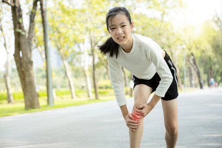 Unhappy asian child girl injured her leg pain or calf muscle while playing in sunny day, female...