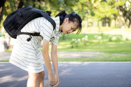 Stress asian child girl carrying heavy school bag or backpack, female teenage feeling pain on back, full of books on her back, going to school for the first time, tired student back to school learningの写真素材