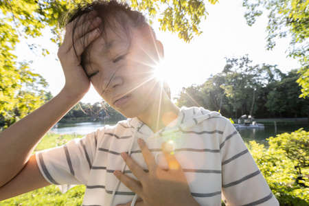 Tired asian woman suffer from sunburn very hot in summer weather problem feel faint,dizzy,difficulty breathing,female teenage with heat stroke,high temperature,burning heat wave hot sun on sunny dayの写真素材