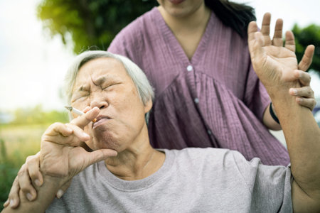 Asian senior mother holding a cigarette smoking,female old in wheelchair smoking near daughter,woman...