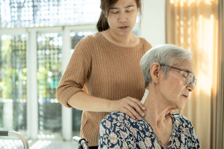 Asian senior mother have nerve pain,shoulder ache,neck pains,female caregiver or daughter massaging her shoulders, frustrated elderly woman,feeling exhausted,neck painful,muscle soreness,inflammationの写真素材