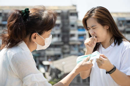 Elderly asian people Chinese is sharing mask to woman who are sick of cough,give protective mask to reduce the risk of spread of germs,Coronavirus outbreak,epidemic of Covid-19 virus to other peopleの写真素材