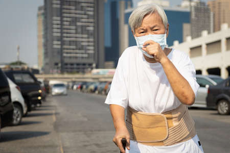 Asian senior woman with protective mask because dirty air,polluted,smog,PM2.5,elderly people wearing face mask to protect respiratory disease outdoor in city street,concept of air pollution,fine dustの写真素材