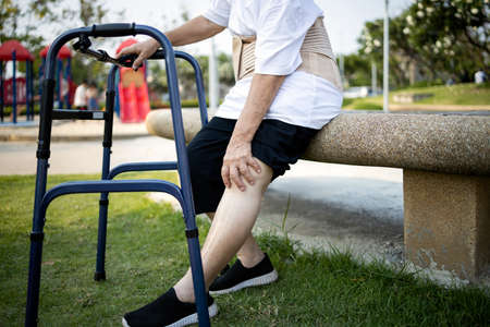 Asian senior woman sitting and massaging her knee,have leg knee pain,female elderly with acute knee joint pain,bone problem,physical injury,exhausted old people suffer from gout,arthritis,rheumatismの写真素材
