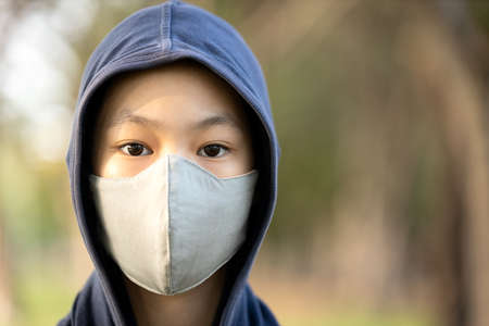 Asian child girl in hood and wearing cotton mask,protection from Covid-19 virus,prevent infection of Coronavirus,pandemic of seasonal influenza,cold,outbreak of contagious disease in the respiratoryの写真素材