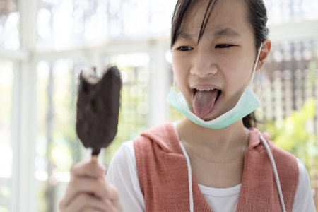 Sick asian child girl having problems with taste of ice cream,loss of taste and impaired sense of...
