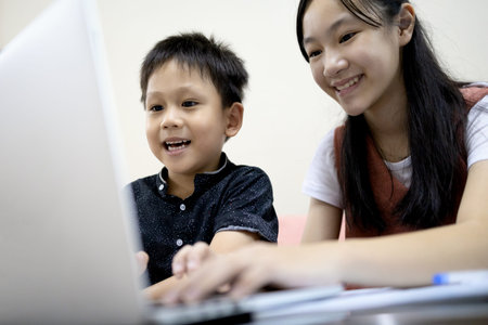 Siblings Kid boy and child girl are enjoying playing online game on laptop computer,asian...