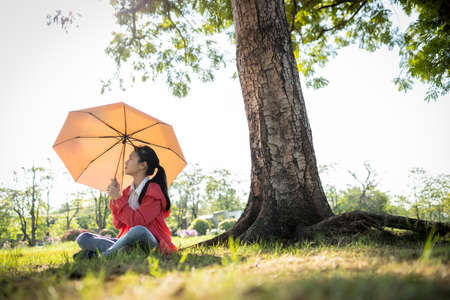 Tired asian child girl is holding umbrella uv to covering face skin,protection from sunlight ray,high temperature on sunny day,prevent heatstroke,sunburn very hot in summer weather problem,feel faintの写真素材