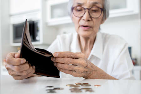 Female senior holding empty wallet,old people shaking out money coins in wallet,financial problems in the retirement age of elderly,planning savings,poverty during Coronavirus crisis,economic downturnの写真素材