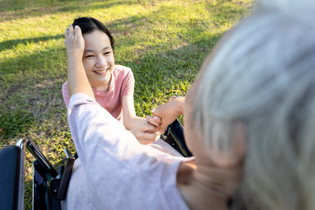 Senior woman in her wheelchair,elderly grandmother is stroking her loving granddaughter head,old...