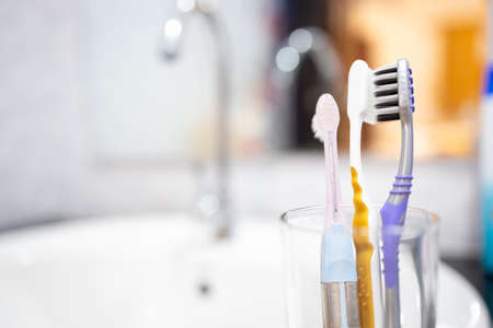 Toothbrushes are kept close together in the glasses,avoid keeping toothbrush heads close together,separate to safety,prevent the spread of COVID-19,pandemic of Coronavirus disease,new normal conceptの写真素材