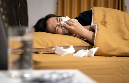 Sick asian woman is ill with a cold flu or sinus virus disease,sinusitis ,runny nose is blowing her...