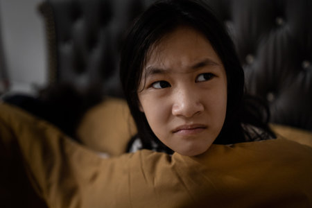 Stressed asian child girl suffering nightmare,waking up at night on her bed in the dark...