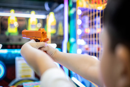 Asian little child playing shooting game for a carnival while visiting in the shopping mall,happy...