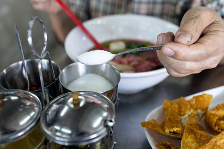 Hand of senior woman holding spoon full of white cane sugar,old elderly eat food that tastes...
