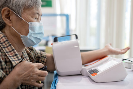 Asian senior woman check blood pressure with digital blood pressure gauge,old elderly patient wear...