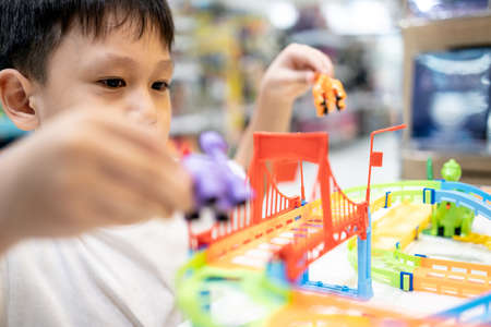 Happy kindergarten kid boy playing with rail road toy game,asian little child having fun enjoy with toys car in nursery,educational toys for children,leisure activity,education development conceptの写真素材