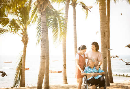 Happy asian old elderly relaxing enjoying a beautiful view by the sea beach on vacation,smiling senior woman with family strolling on sea shore on holiday,travel in summer,travel lifestyle conceptの写真素材