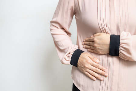 Asian woman patient with abdominal pain on right side belly,painful in abdomen,irritable bowel disease,lady girl holds under the ribs,stomach ache,cirrhosis of the liver disease,liver cancer conceptの写真素材