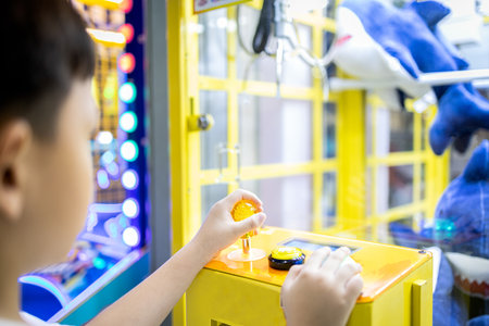 Kid boy playing claw crane machine,fun enjoy,arcade game with toys inside,little child catching the doll during shopping in a mall,skill training game,children's holiday activity,vacation conceptの写真素材