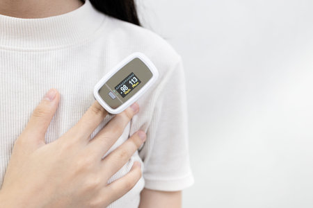 Hand of lady woman with an attached pulse oximeter on finger or fingertip for examination of the...