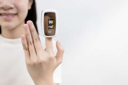 Hand of asian child girl with an attached pulse oximeter on fingertip,lady measuring heart rate,checking oxygen saturation level in the blood,diagnosis of or  at home,health careの写真素材