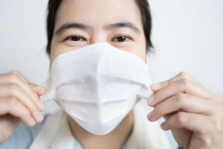 Woman was holding the side of the medical face mask with hands to move slide the face mask up after dropped from the noseの写真素材