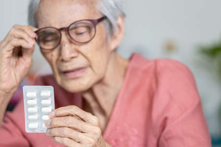 Old elderly having trouble with very small fonts size on product,hard to read and see,too small letter on the medicine labels,problem of printing small letters from the manufacturer,Consumer problemsの写真素材