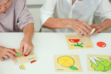 Asian senior woman holding jigsaw puzzle pieces,old elderly playing a  jigsaw puzzle games with her friend,leisure activities,development of brain,prevent Alzheimer's disease and dementia problemsの写真素材