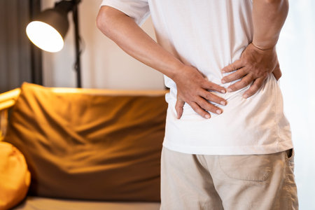 Sad asian man having a backache after sleep,Stressed people suffering from low back pain,lumbar disc...