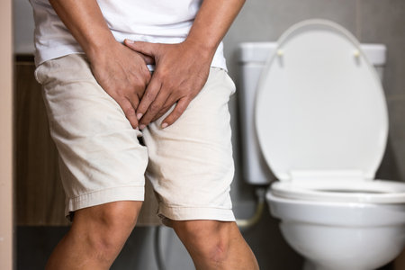 Asian middle aged man suffering from dysuria,acute cystitis, urinary tract infection,people patient holding crotch in toilet,prostate problems,inflammation of urethra,painful or difficult urinationの写真素材