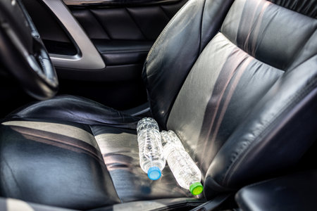 Plastic bottle of water placed on car seat and exposed to sun in sunny day,bottle of drinking water in car,sunlight,very hot,heating temperature,cause danger if parked in the sunshine for a long timeの写真素材