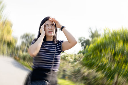 Dizzy woman suffering from vertigo,sensation of whirling,spinning around,loss of balance,she walked with stagger,vertigo while walking outdoor,symptom of giddiness,dizziness attack,health care conceptの写真素材