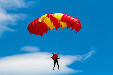 Skydiver and colorful parachute on blue sky background.の素材