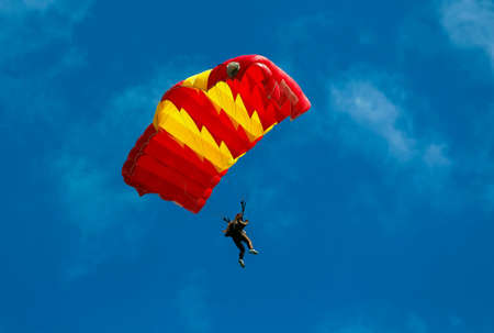 Skydiver and colorful parachute on blue sky background.の素材