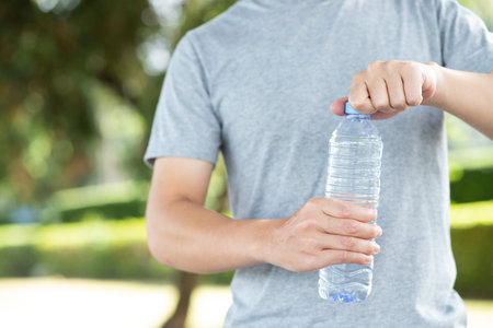 Hand holding water bottle in the park
