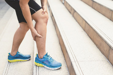 Runners who touch a painful, twisted or broken ankle, an athlete-training accident Running sprains an ankle injury to the knee and pain in the thigh to show pain.の写真素材