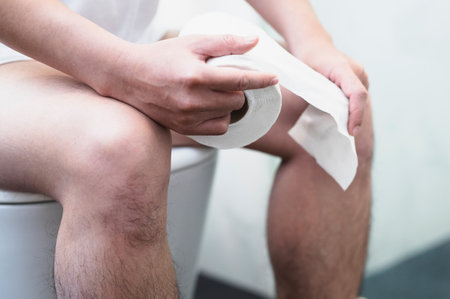 Man suffering from knee pain while sitting on toilet bowl at the hospitalの写真素材