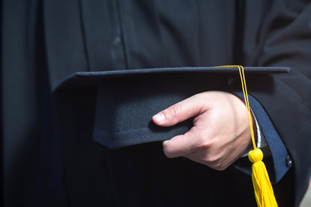 Close up of graduation cap with yellow tassel in hand.の写真素材