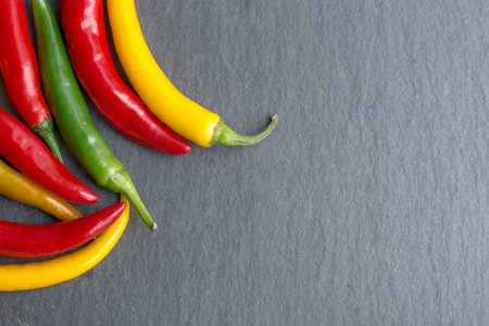 Vibrant peppers on dark slate, flat lay, top view